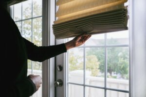 Woman Adjusts Roman Shade on French Door