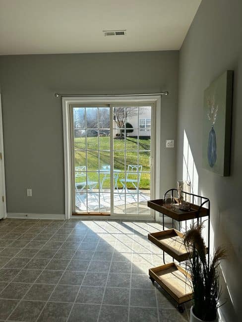 A sunlit room with glass patio doors opening to a green lawn