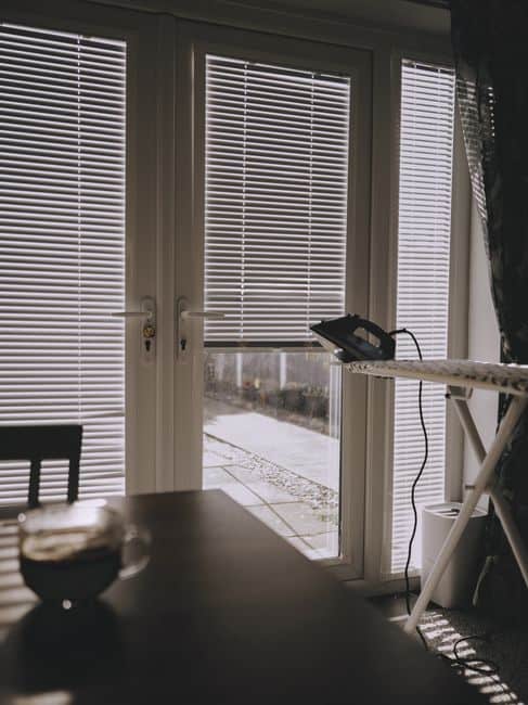 Horizontal blinds on a glass door in a sunlit room