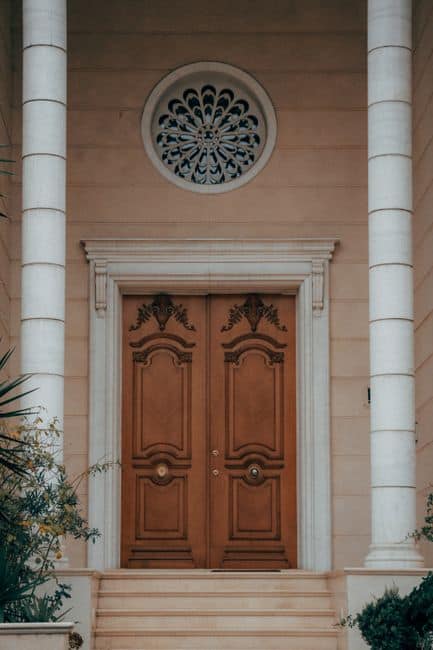 A pair of carved wooden double doors with a round window above