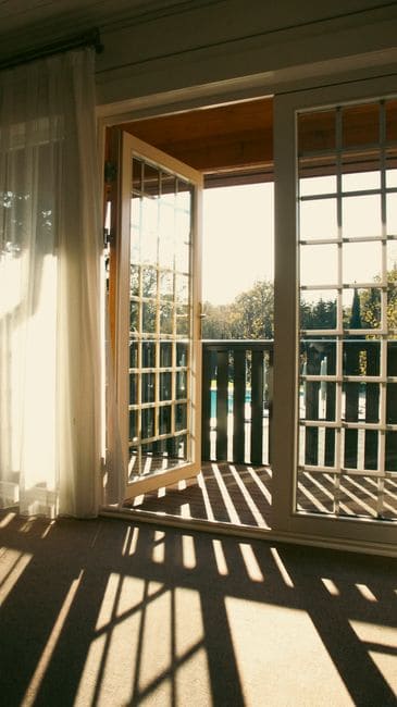 Sunlight through open French doors onto a balcony