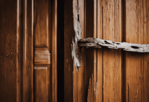 an image of a splintered wooden door frame, cracked plaster surrounding it
